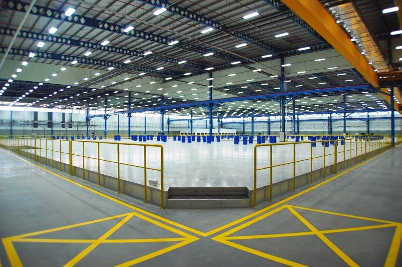 Interior of Spirit AeroSystems SE Asia. Large industrial open room with yellow railing and florescent lighting.