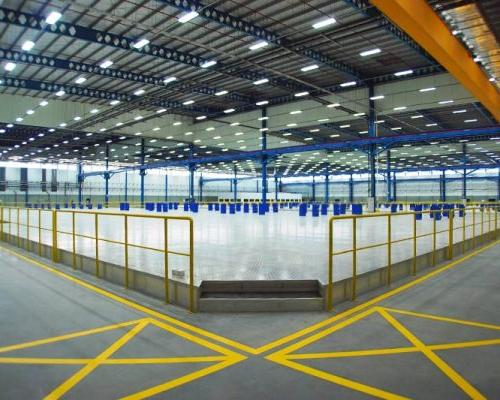 Interior of Spirit AeroSystems SE Asia. Large industrial open room with yellow railing and florescent lighting.